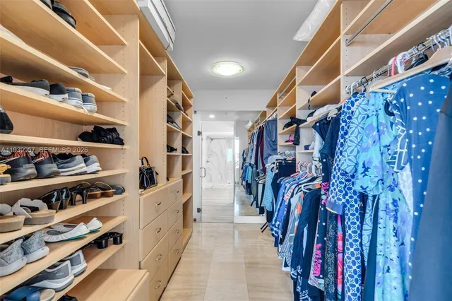 a view of walk in closet with clothes and shoes