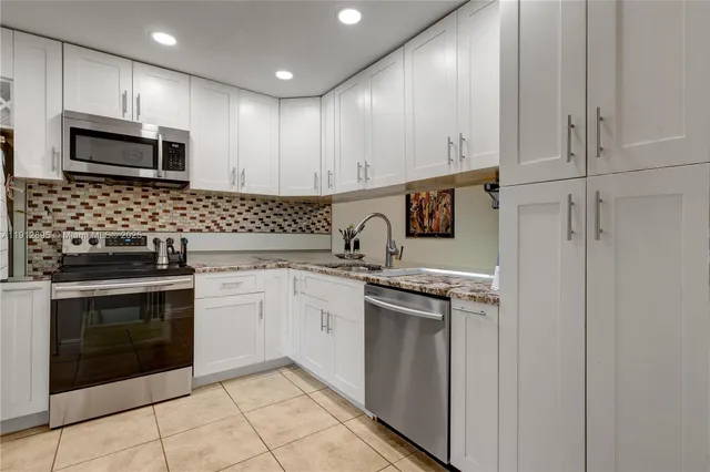 a kitchen with stainless steel appliances granite countertop white cabinets stove a sink and dishwasher