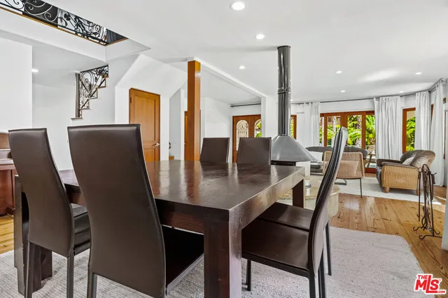 a dining hall with stainless steel appliances granite countertop a stove a sink a refrigerator and chairs