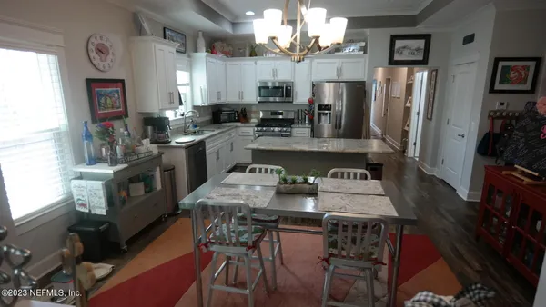 a kitchen with stainless steel appliances kitchen island granite countertop a table chairs in it and a window