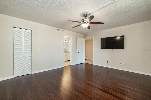 a view of an empty room with wooden floor and a flat screen tv
