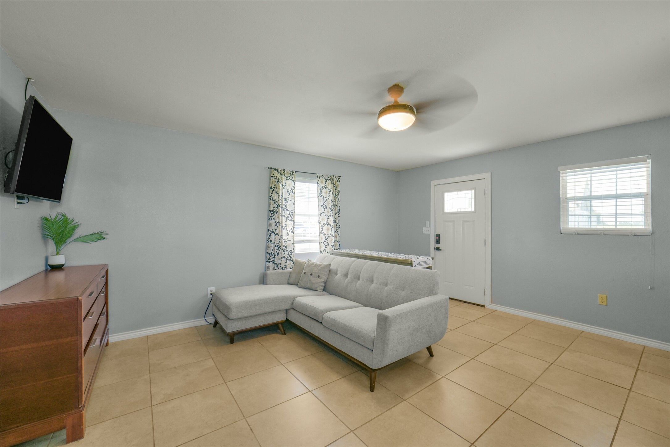 11301 South FM 441 Road El Campo, TX 77437 - Photo 29 of 43 This bright living room features neutral tile flooring, a modern ceiling fan, and ample natural light from two windows.