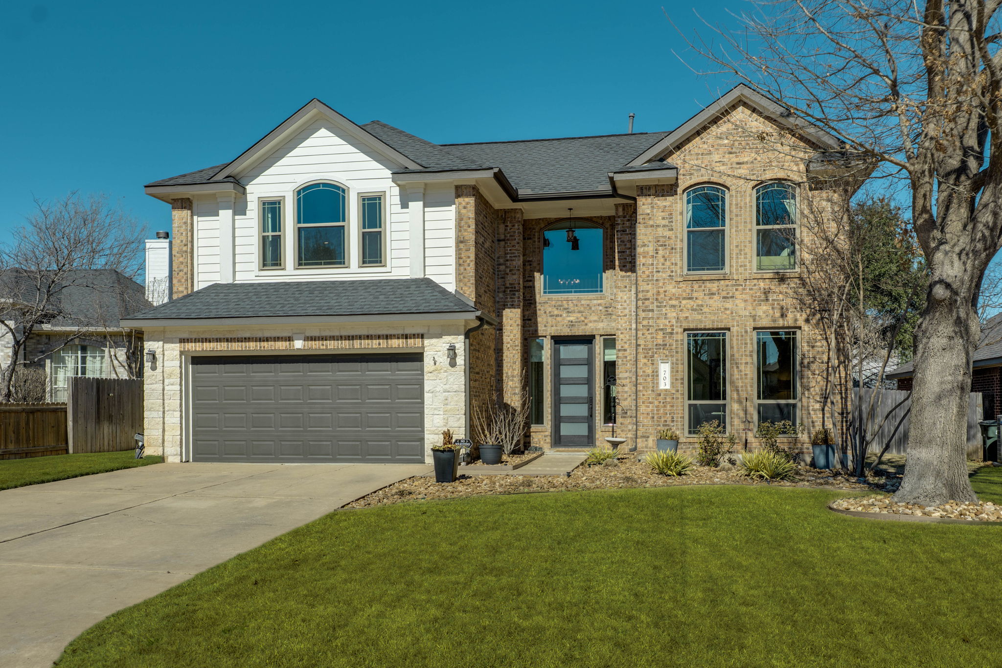 View of front of home with a garage, concrete driveway, a shingled roof, and brick siding