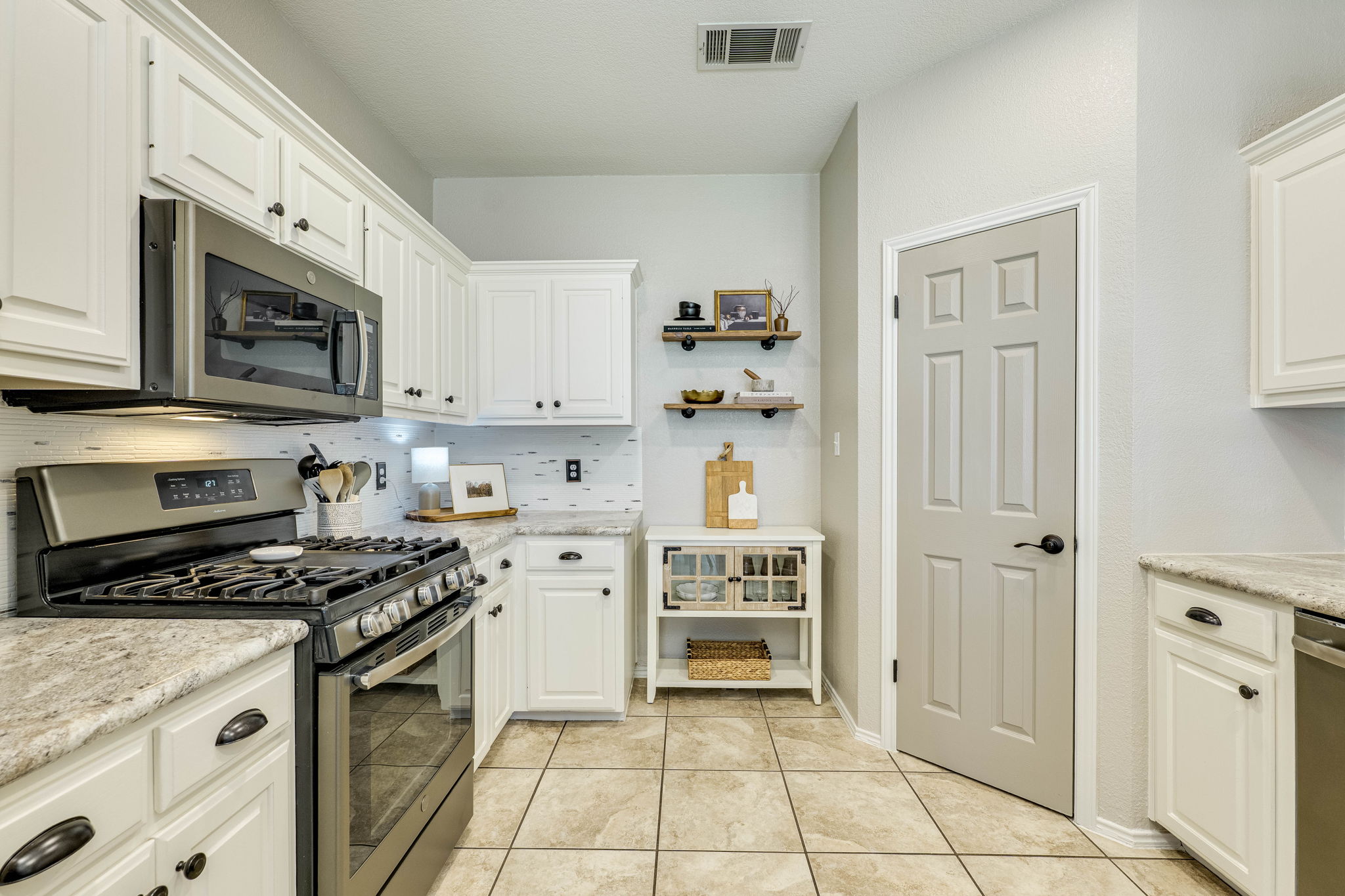 703 Ridge View Drive Leander, TX 78641 - Photo 16 of 39 Kitchen with stainless steel appliances, open shelves, white cabinets, light tile patterned floors, and decorative backsplash