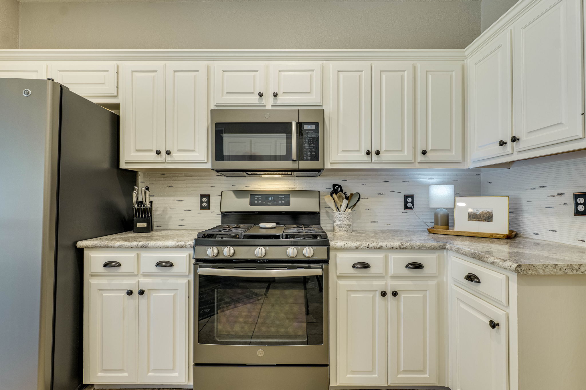 703 Ridge View Drive Leander, TX 78641 - Photo 17 of 39 Kitchen with stainless steel appliances, backsplash, white cabinets, and light stone counters