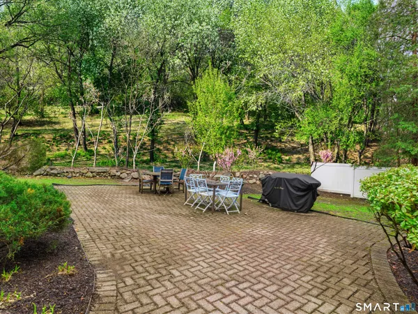 a view of a patio with table and chairs potted plants and large tree