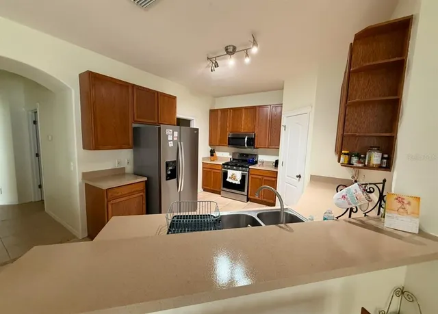 a kitchen with stainless steel appliances kitchen island granite countertop a refrigerator a stove and a sink dishwasher with wooden floor