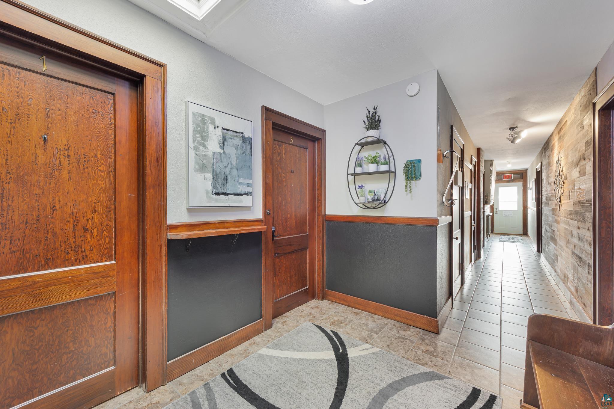 601 1st Avenue Two Harbors, MN 55616 - Photo 23 of 99 Hallway allowing access to the STR apartments, entrance staircase, laundry room, backdoor and back deck - featuring original Douglas fir woodwork
