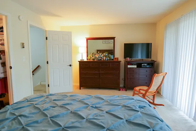 a bedroom with a bed and a flat tv screen on dresser