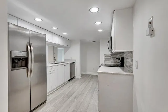 a kitchen with a refrigerator sink and cabinets