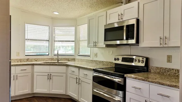 a kitchen with stainless steel appliances granite countertop white cabinets granite counter tops and a window