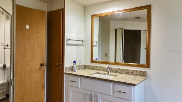 a bathroom with a granite countertop sink and a mirror
