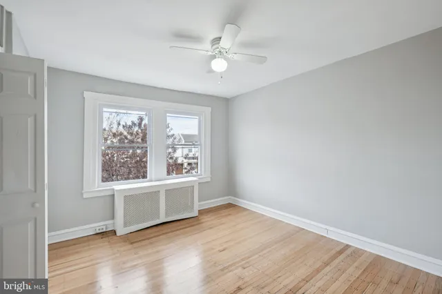 an empty room with wooden floor fan and windows