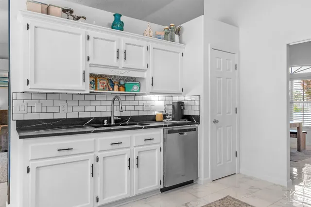 a kitchen with granite countertop white cabinets and stainless steel appliances