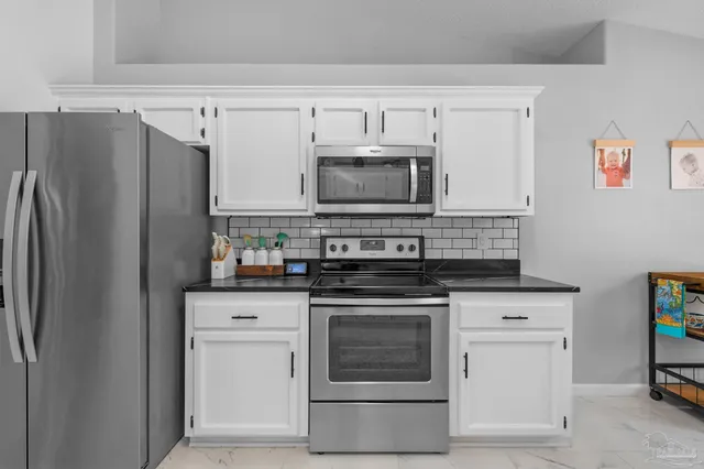 a kitchen with granite countertop white cabinets and stainless steel appliances