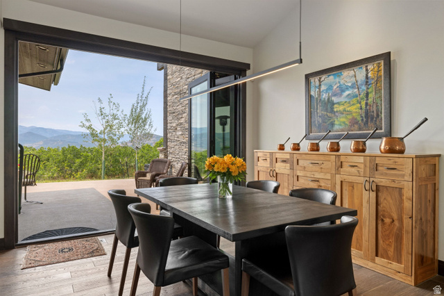 11547 Soaring Hawk Lane Hideout, UT 84036 - Photo 5 of 43 Open-concept dining area featuring wood-finish flooring, a linear pendant light fixture, and a full-height glass sliding door opening to an outdoor patio