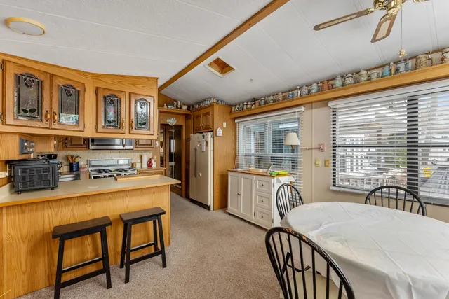 a dining hall with stainless steel appliances granite countertop a stove a sink a dining table and chairs with wooden floor