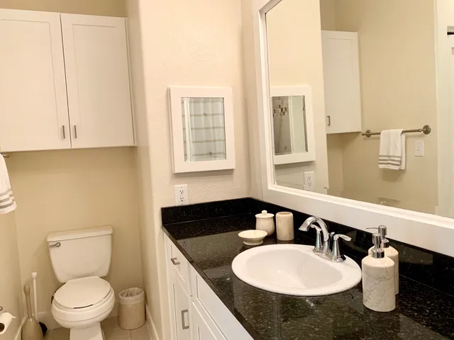 a bathroom with a granite countertop sink toilet and mirror