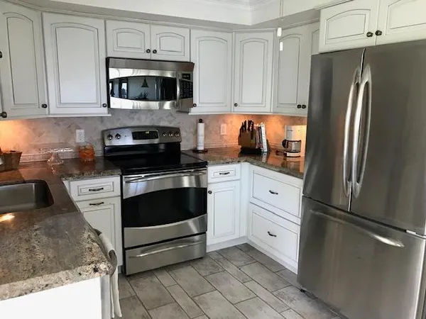 a kitchen with white cabinets and stainless steel appliances