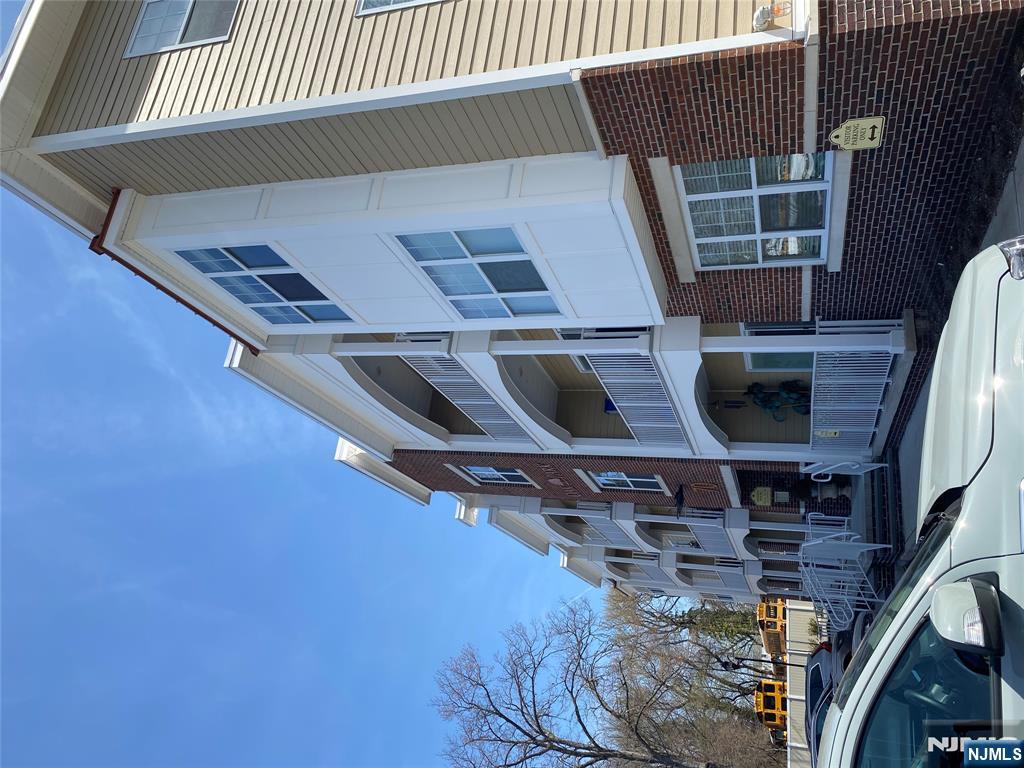 a front view of a building with lot of cars and trees