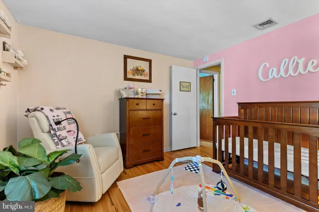 a bedroom with furniture a baby crib and a wooden floor