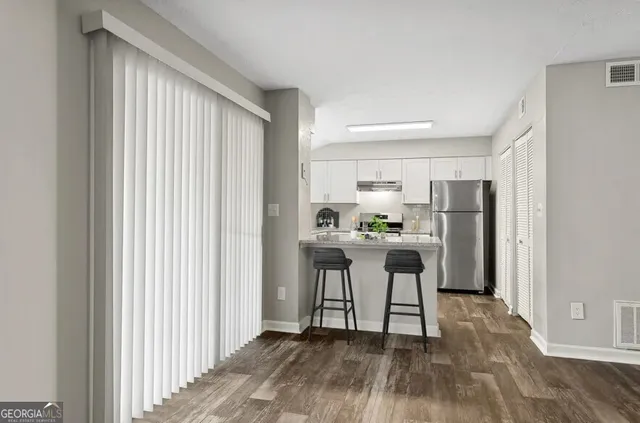 a view of kitchen with stainless steel appliances wooden floor and chair