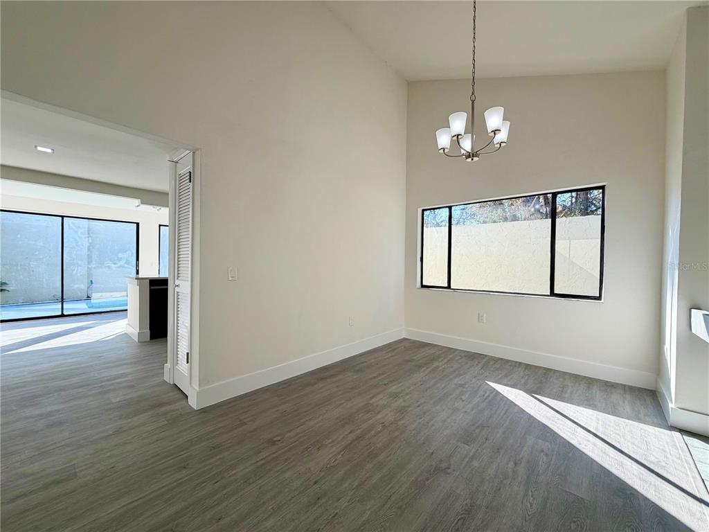 7314 Patio Row Hudson, FL 34667 - Photo 8 of 17 an empty room with wooden floor chandelier and windows