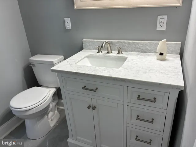 a bathroom with a granite countertop toilet sink and mirror