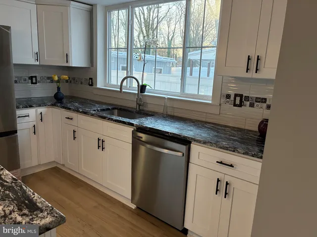 a kitchen with granite countertop a sink a stove and cabinets