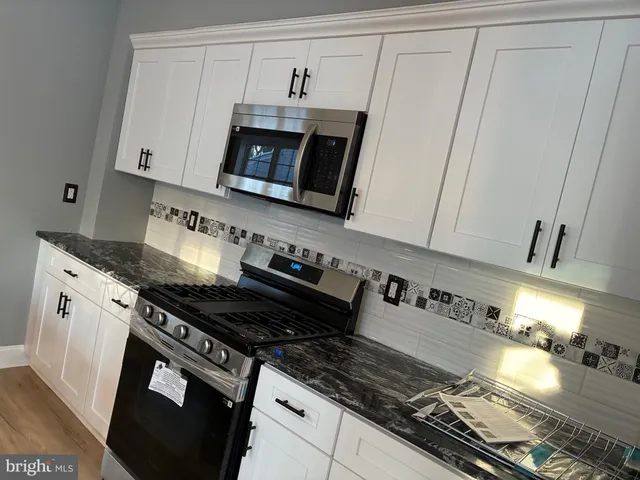 a kitchen with granite countertop a stove and a microwave