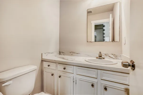a bathroom with a toilet sink vanity and mirror