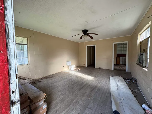 an empty room with windows and fan
