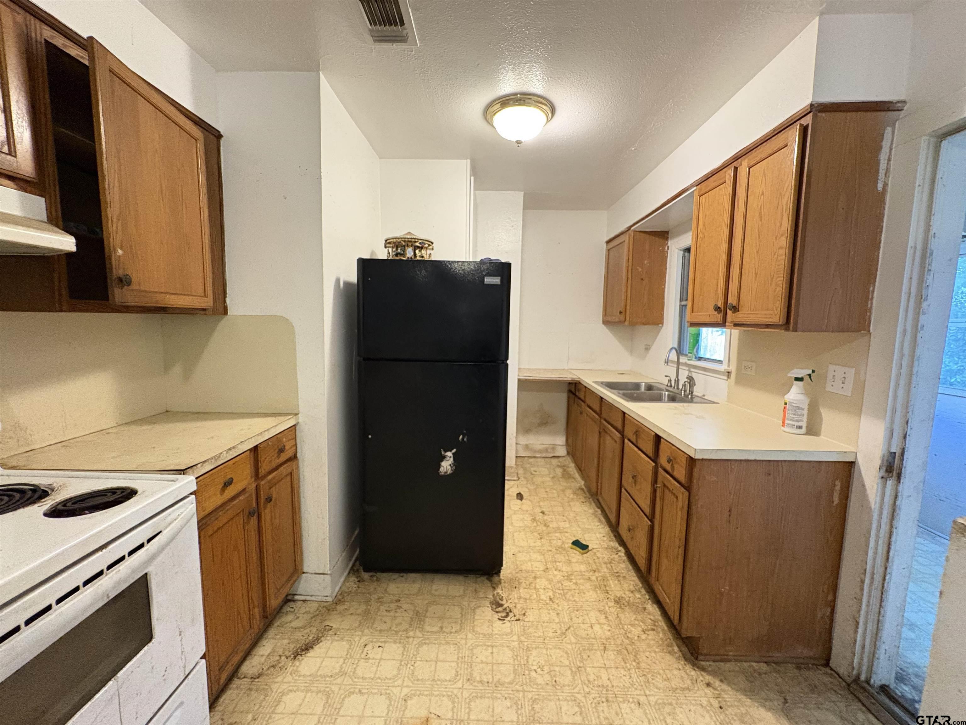 110 East 9th Street Mount Pleasant, TX 75455 - Photo 24 of 27 a kitchen with a refrigerator and a sink