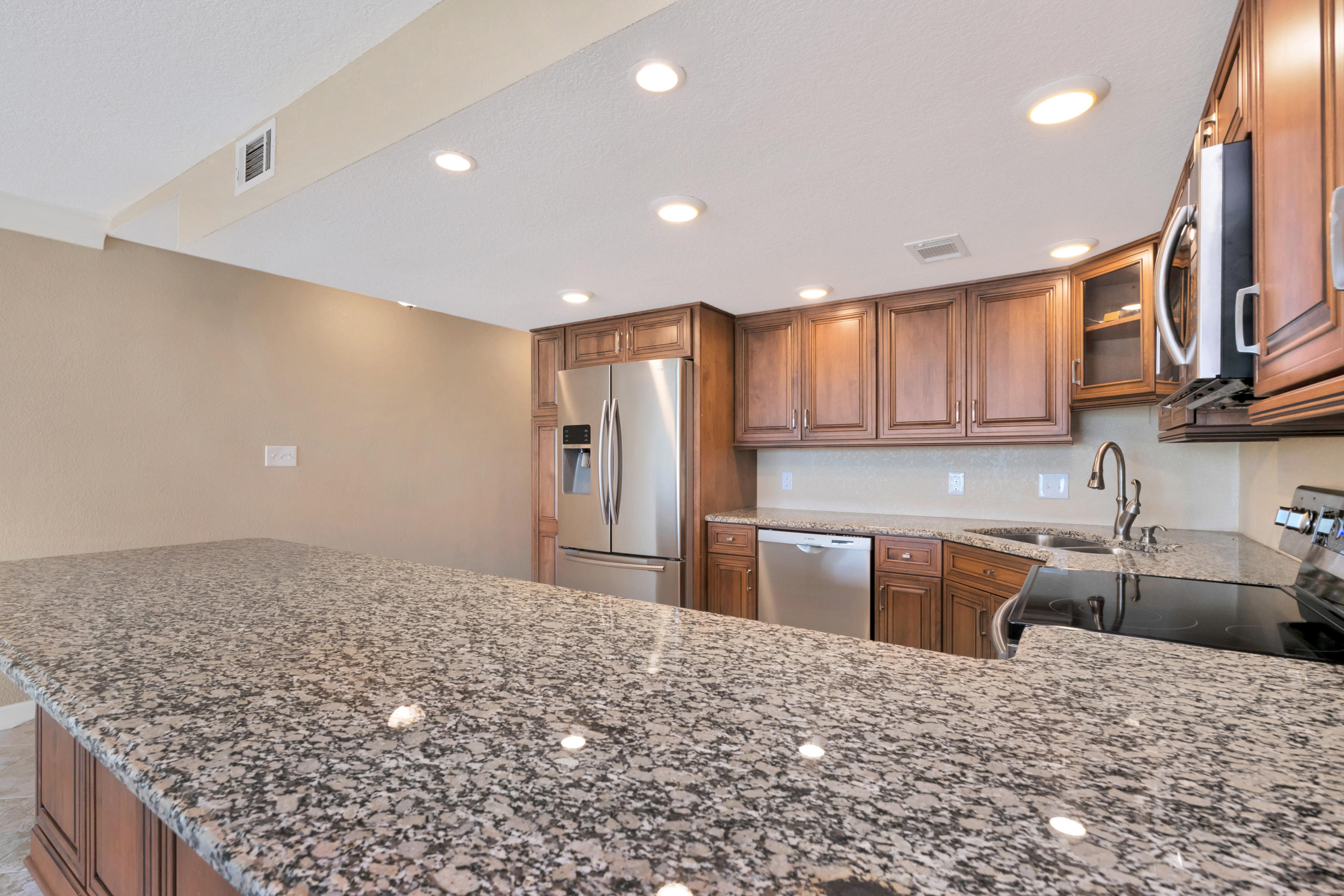 151 Calhoun Avenue, Unit 409 Destin, FL 32541 - Photo 8 of 15 a kitchen with stainless steel appliances kitchen island granite countertop a refrigerator and cabinets