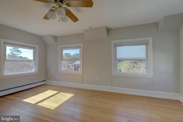a view of empty room with wooden floor and fan