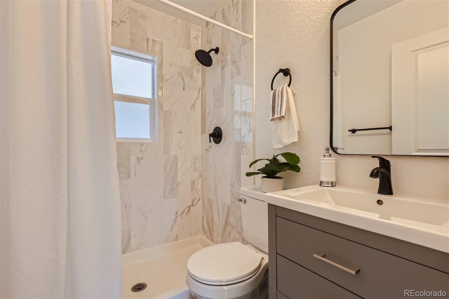 3090 Pierce Street Wheat Ridge, CO 80214 - Photo 14 of 28 a bathroom with a sink a toilet and shower