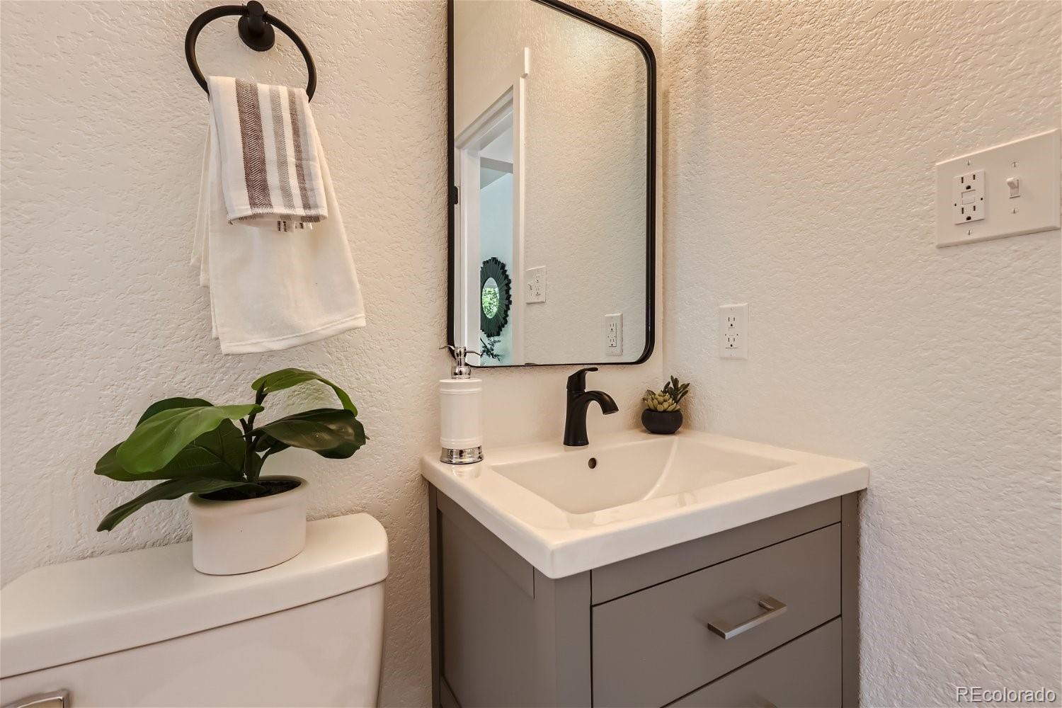 3090 Pierce Street Wheat Ridge, CO 80214 - Photo 21 of 28 a bathroom with a sink a toilet and mirror