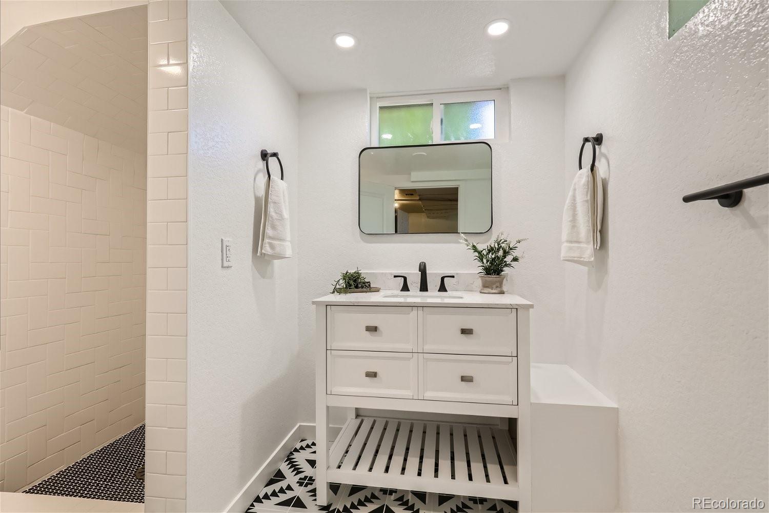 3090 Pierce Street Wheat Ridge, CO 80214 - Photo 22 of 28 a bathroom with a sink a mirror and shower
