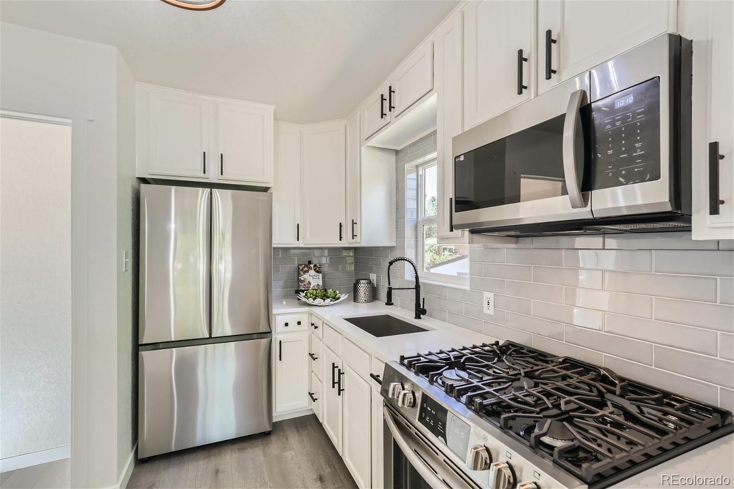 3090 Pierce Street Wheat Ridge, CO 80214 - Photo 10 of 28 a kitchen with stainless steel appliances granite countertop a stove a refrigerator and a microwave