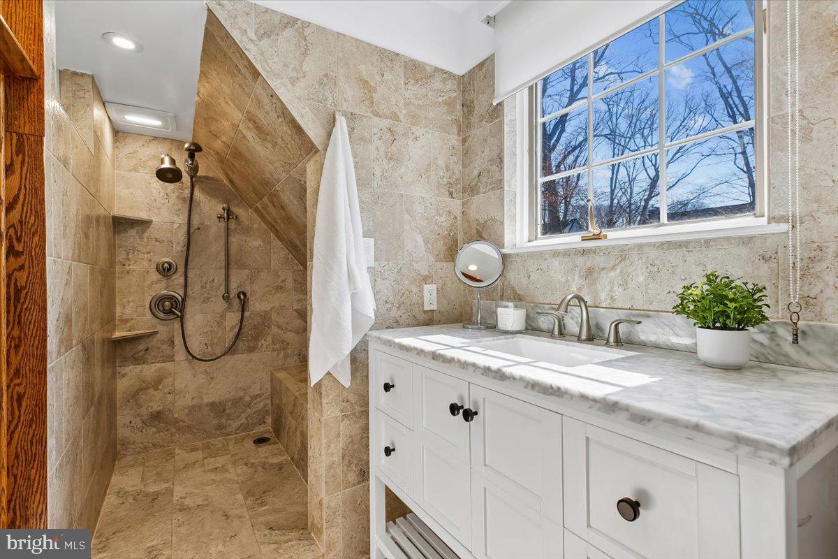 6317 Poe Road Bethesda, MD 20817 - Photo 22 of 43 a bathroom with a granite countertop sink a mirror and shower