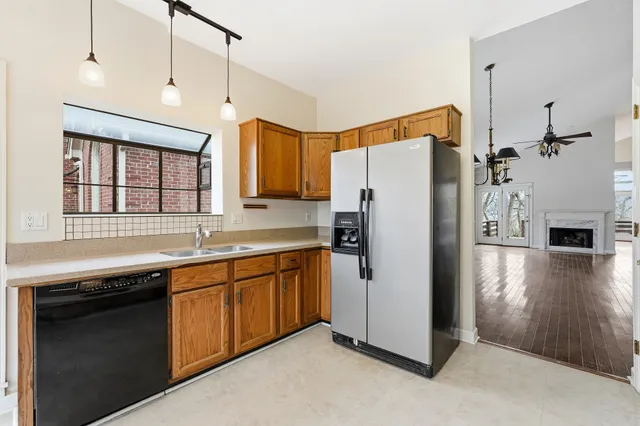 a kitchen with stainless steel appliances granite countertop a refrigerator a sink dishwasher a stove with wooden cabinets