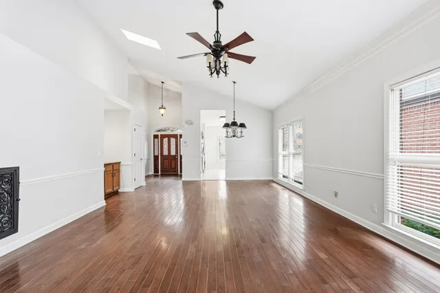 a view of empty room with wooden floor and ceiling fan