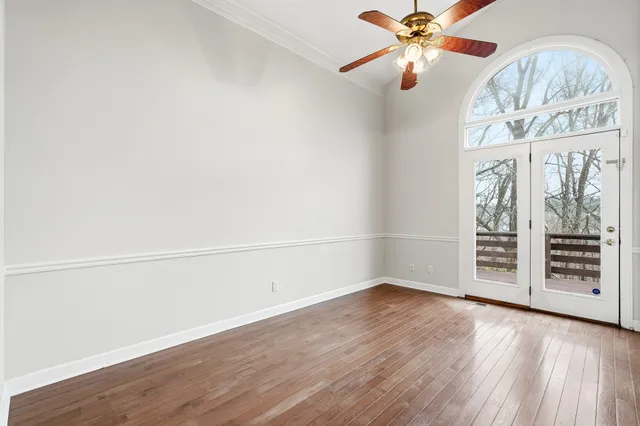 an empty room with wooden floor fan and windows