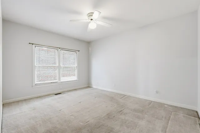 an empty room with a window and a ceiling fan