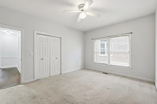 an empty room with chandelier fan and windows