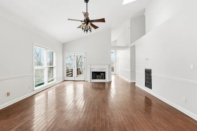 a view of an empty room with wooden floor fireplace and a window