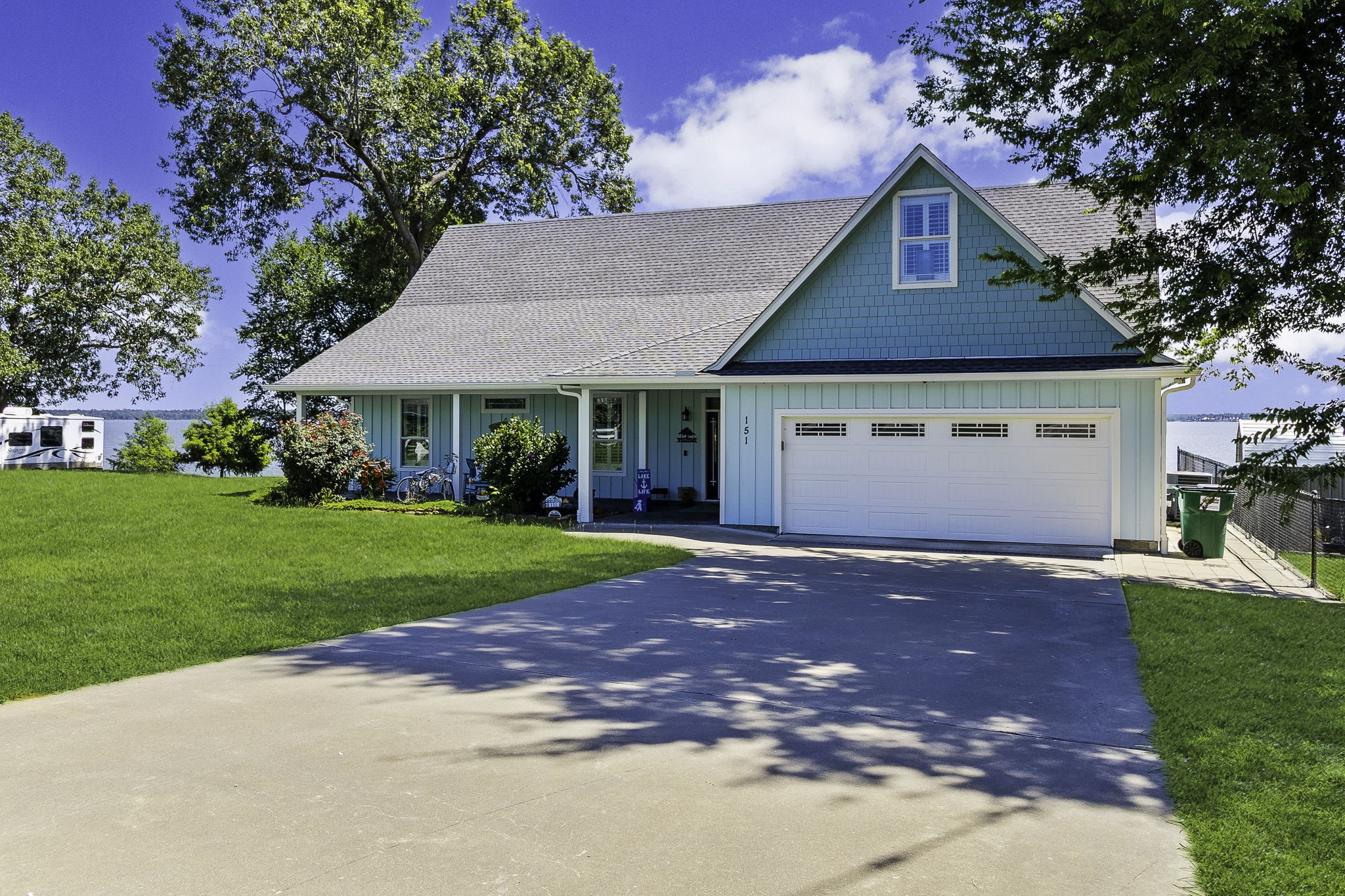 151 Key Largo Loop Point Blank, TX 77364 - Photo 2 of 49 Stunning lakefront home with a spacious driveway, attached two-car garage, and inviting curb appeal.