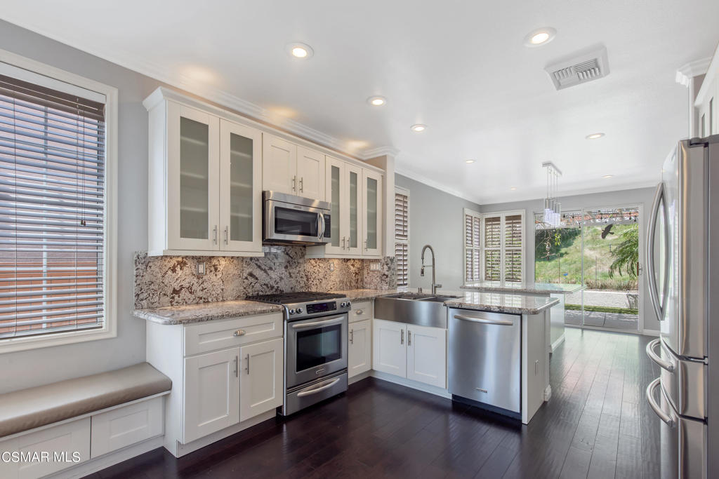 869 Aloe Lane Simi Valley, CA 93065 - Photo 3 of 31 a kitchen with stainless steel appliances granite countertop a stove top oven a sink dishwasher a dining table and chairs with wooden floor
