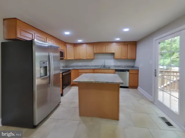 a kitchen with stainless steel appliances granite countertop a refrigerator a sink a stove and a microwave oven