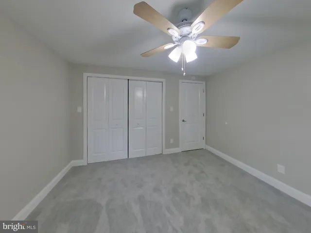 an empty room with a chandelier fan and windows